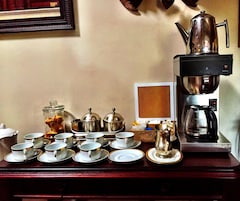 A coffee station with multiple cups, a coffee pot, and containers on a wooden table.