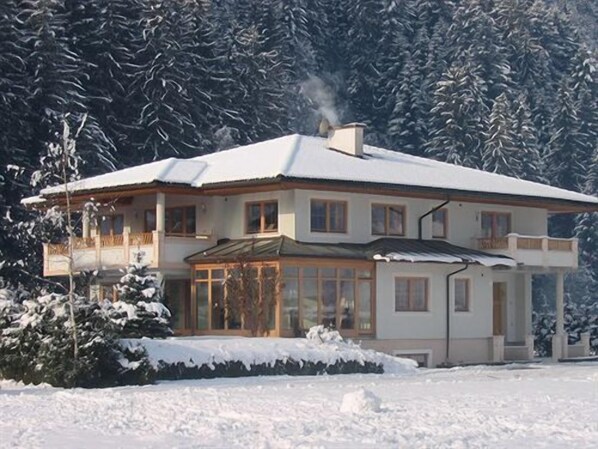 A two-story house with a snow-covered roof and a balcony. - Ferienhof Kampfl (Fuegen)