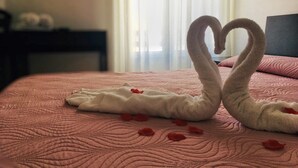 Un letto con una coperta rosa e due asciugamani a forma di cigno.