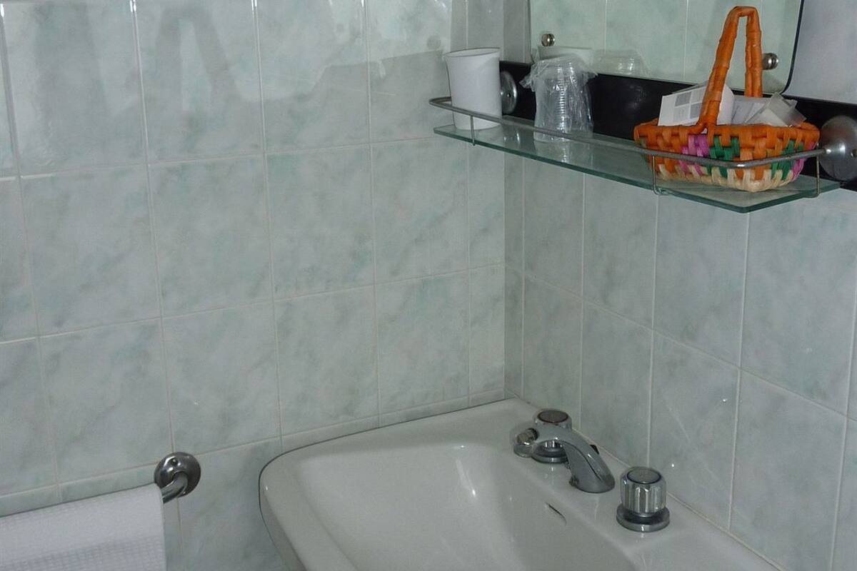 Une salle de bain avec un lavabo blanc, une étagère en verre, un miroir et un porte-serviettes.