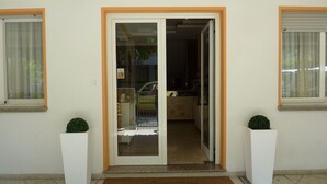 L'ingresso di un edificio con una porta in vetro, un piccolo gradino e due piante in vaso.