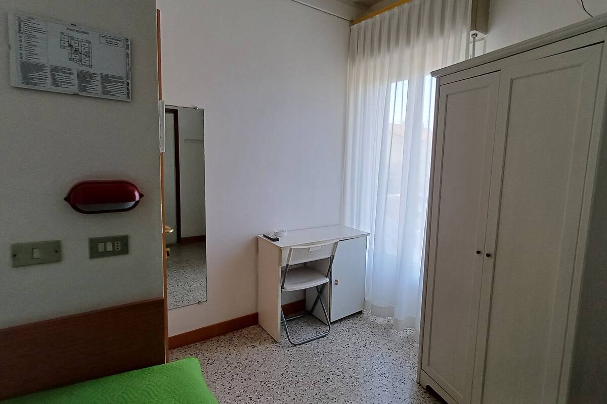 Une pièce comprenant un lit, un bureau, une armoire et un miroir au mur.