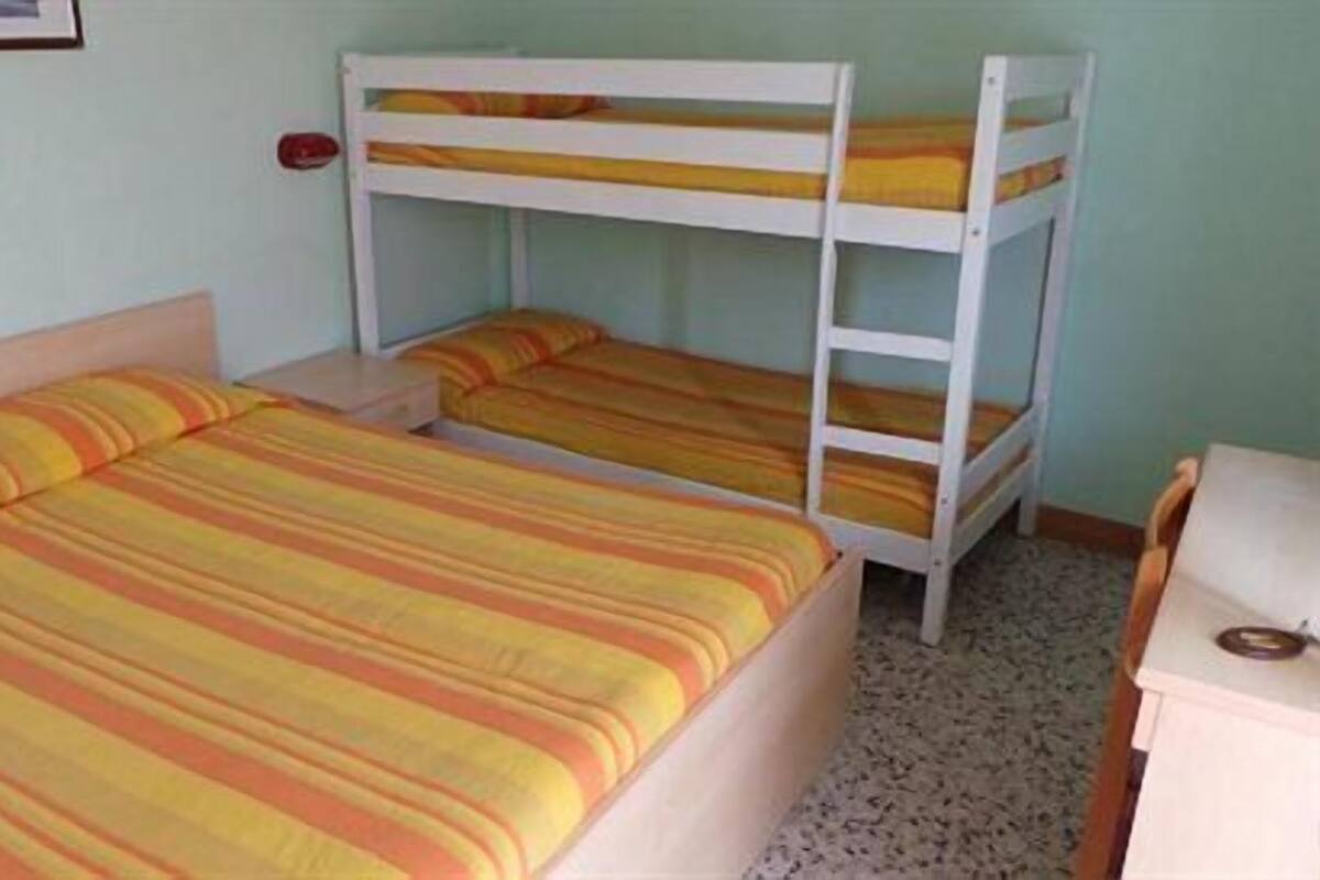 Une chambre avec des lits superposés et un bureau.
