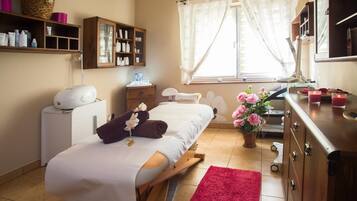 Un dormitorio con una cama, una mesita de noche, un tocador con espejo, un estante con artículos de aseo, una ventana con cortinas y una alfombra roja.