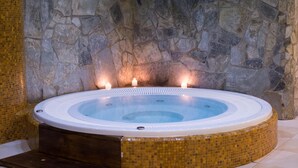 A hot tub with a stone wall backdrop and mosaic flooring. - Hotel Karino Spa (Solina)