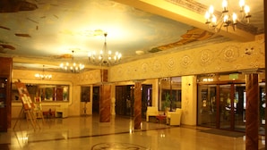 A spacious lobby with a large chandelier, marble columns, and a central emblem on the floor. - Hotel Karino Spa (Solina)