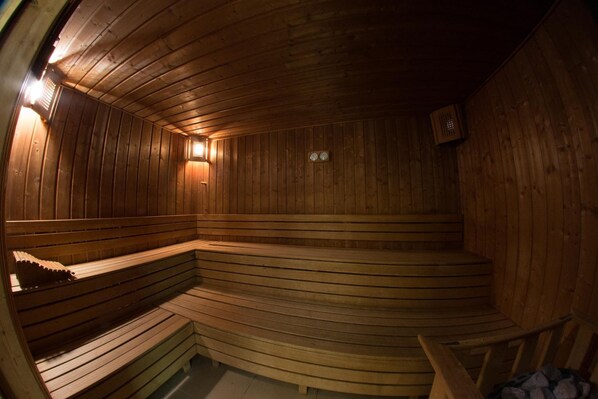 Una sauna de madera con bancos y una zona de asientos curva.
