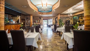 A restaurant with a central open space, tables with white tablecloths, and a chandelier. - Hotel Karino Spa (Solina)