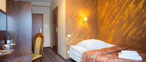 Ein Hotelzimmer mit Bett, Schreibtisch, Stuhl und Wandlampe.