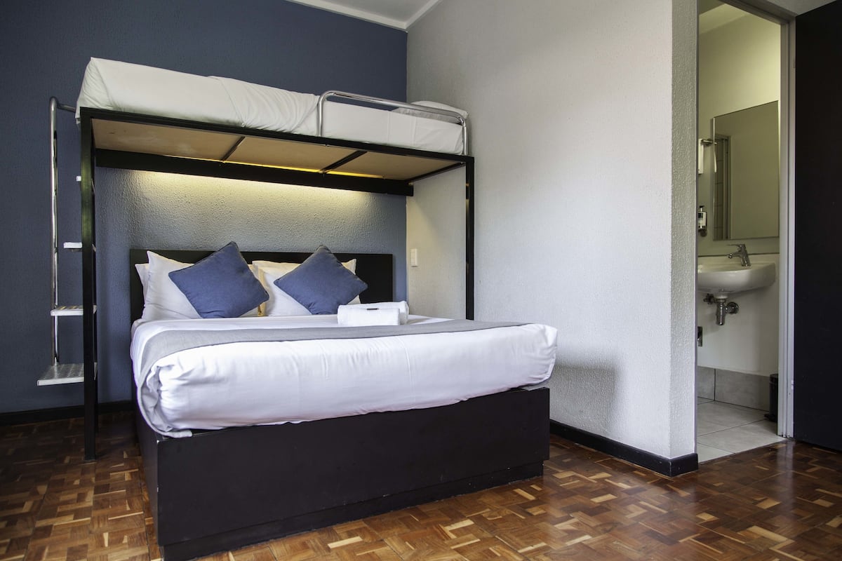 A bunk bed with a headboard, white bedding, and two pillows.