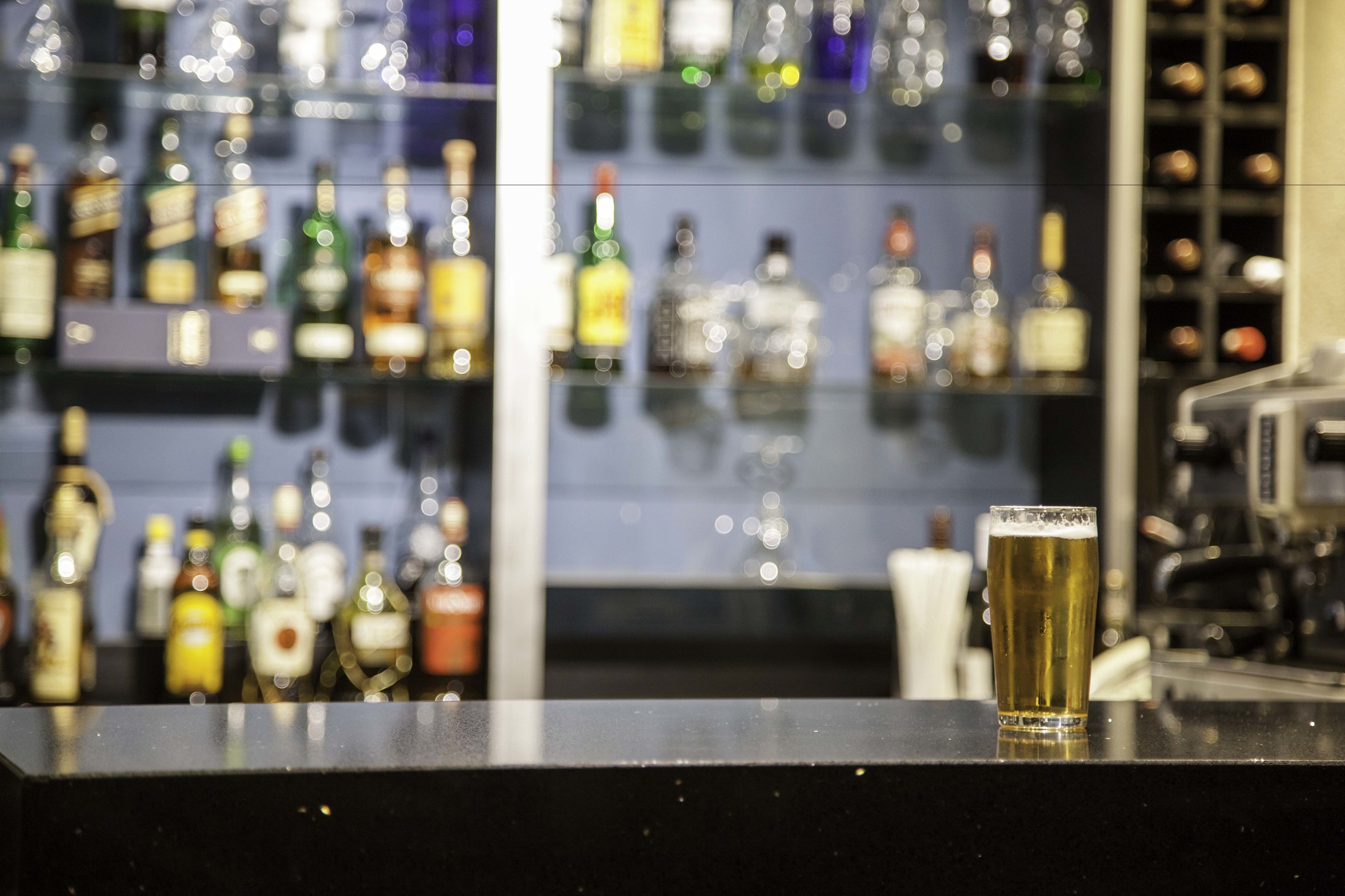 Una barra con una jarra de cerveza y un fondo borroso con varias botellas.