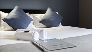 Una cama bien hecha con una toalla blanca doblada y un libro encima.