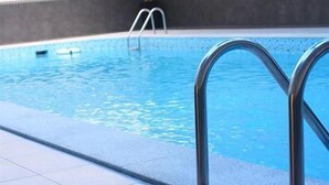 Una piscina con barandales metálicos y un deck cubierto de azulejos.