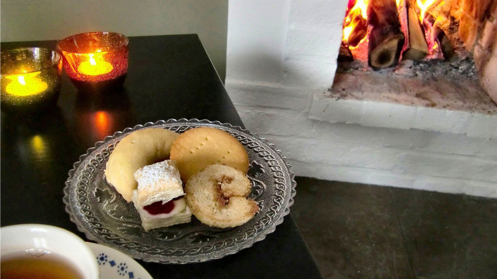 Un piatto di dolci su un tavolo con candele e un camino sullo sfondo.