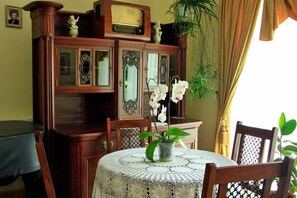 A dining area with a round table covered by a lace tablecloth, surrounded by wooden chairs. - Dwor Wapowce (Przemysl)