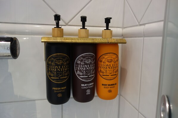 Three bottles of I Love Eco Essentials on a shelf in a bathroom.