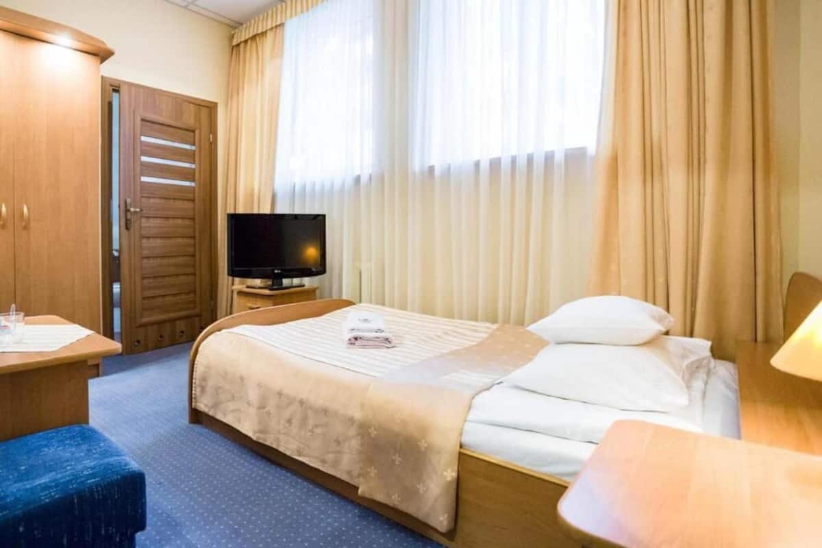 Ein Hotelzimmer mit Bett, Fernseher, Schreibtisch und Stuhl.