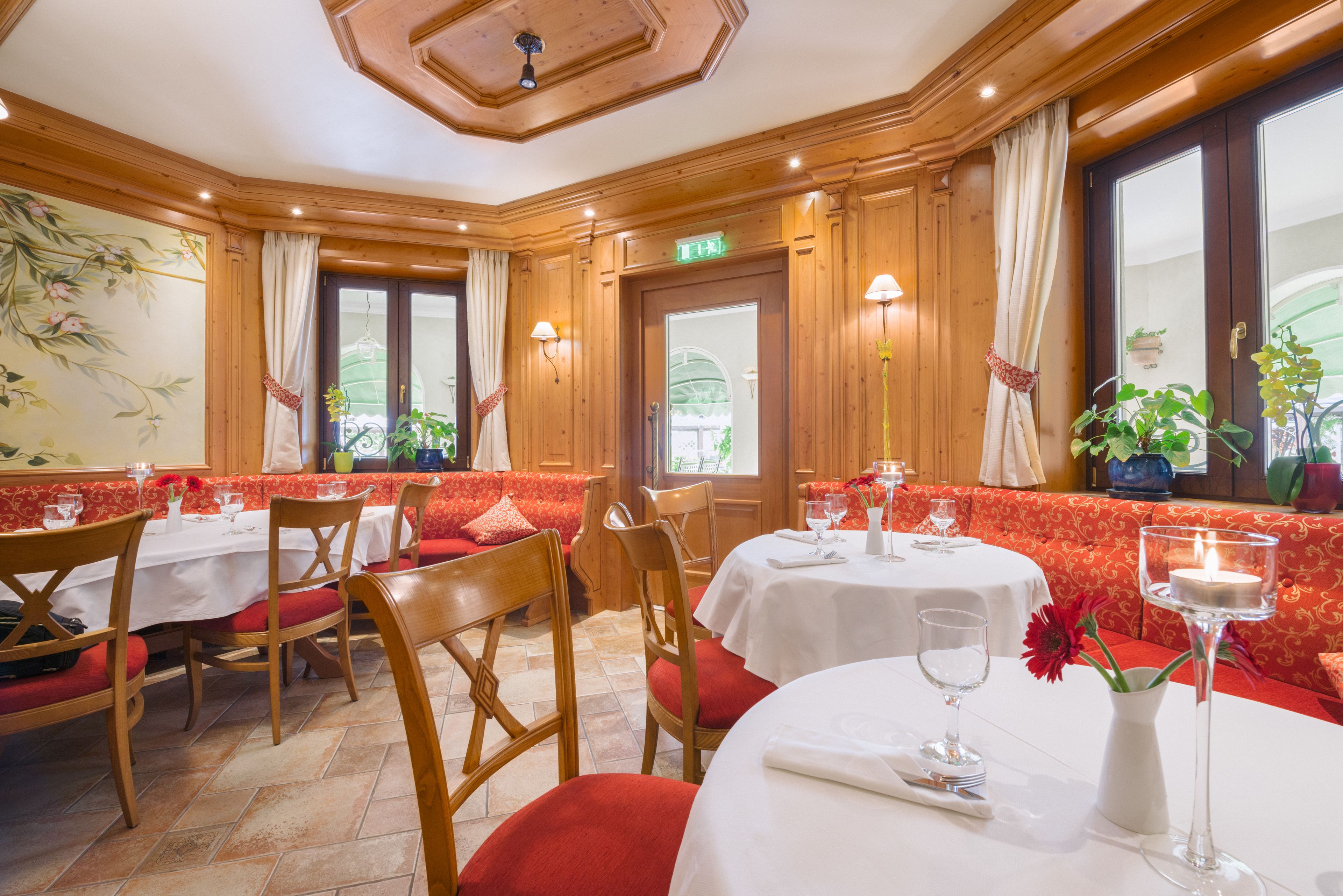 A restaurant with wooden paneling, red cushioned seating, and white tablecloths.