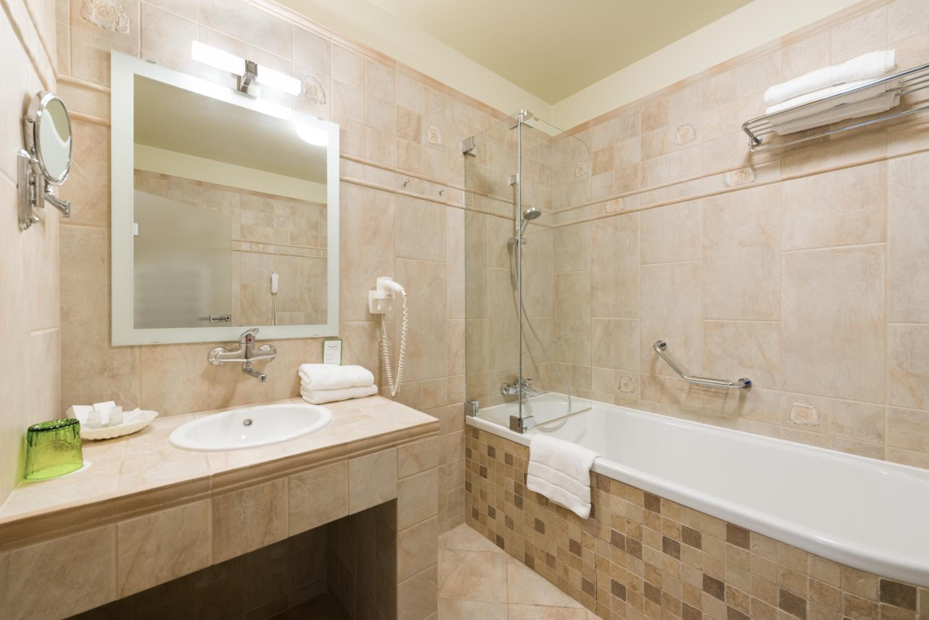 A bathroom with a sink, mirror, and bathtub.