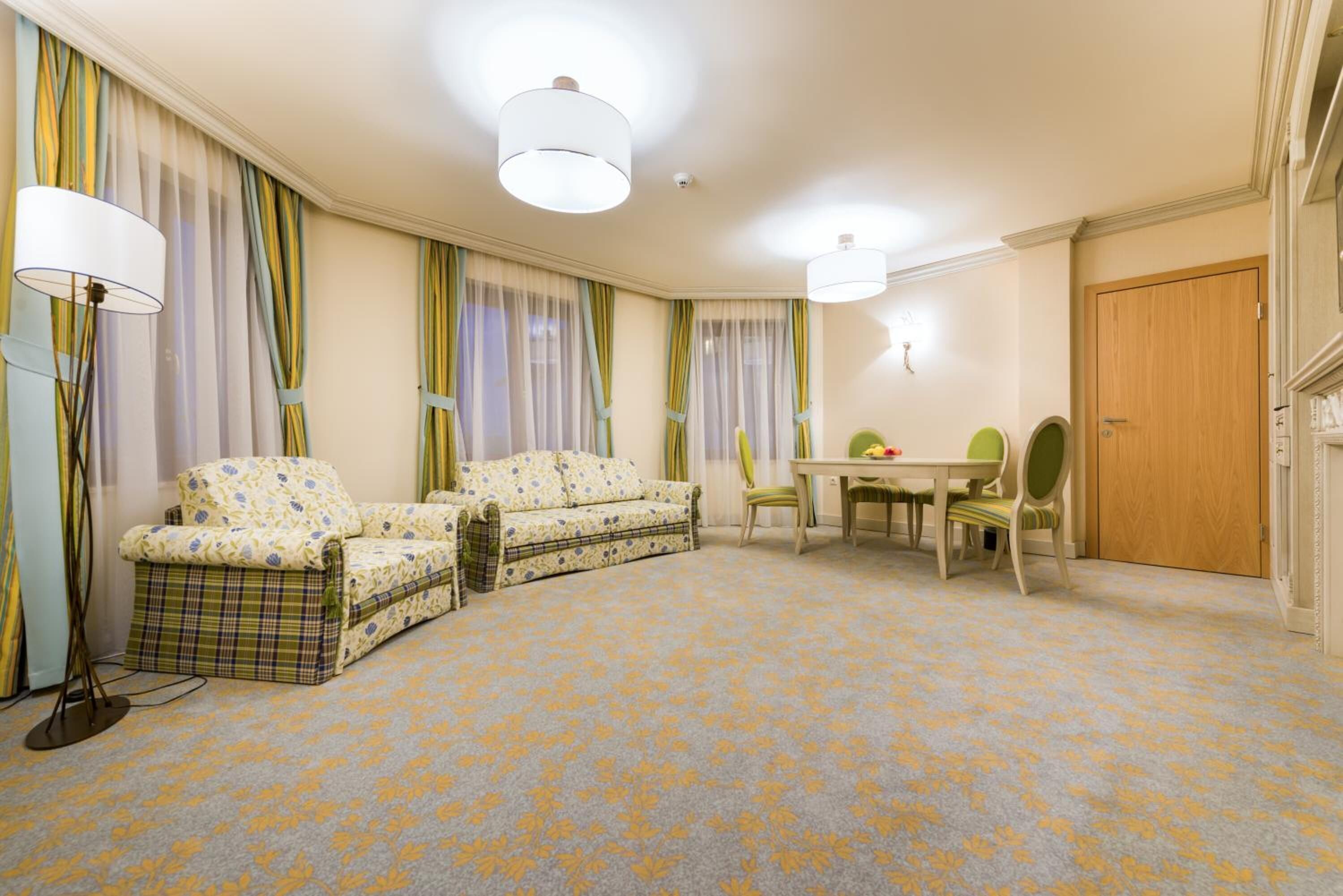 A room with a sofa, a dining table with chairs, and a door.