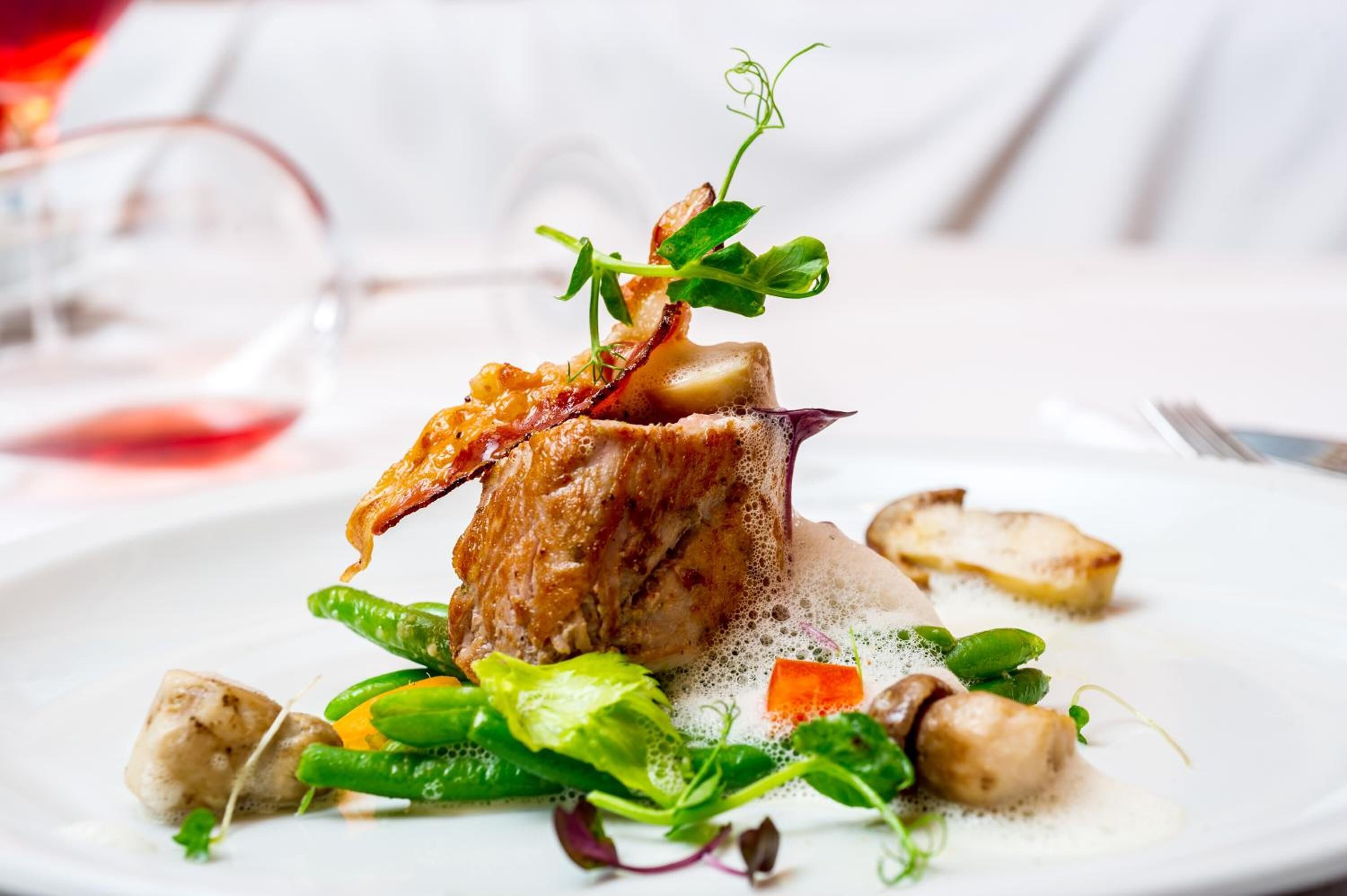 Ein Teller mit Essen, darunter Fleisch, Gemüse und ein Glas Rotwein.