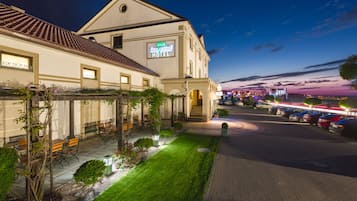 Un hotel con un letrero que dice "Sonnenhof HOTEL" y un jardín bien cuidado con bancos y plantas.