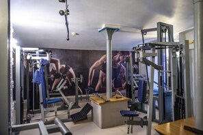 Un gimnasio con diversos equipos de ejercicio, incluyendo máquinas de pesas y bancos.