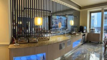 En hotellobby med en receptionsdisk, en tv och en sittgrupp.