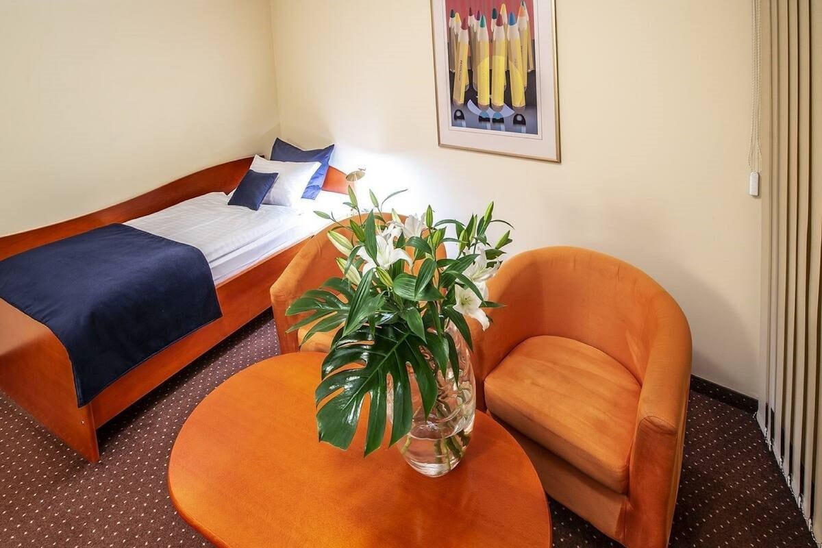 Una habitación de hotel con una cama, una silla y una mesa con una planta.