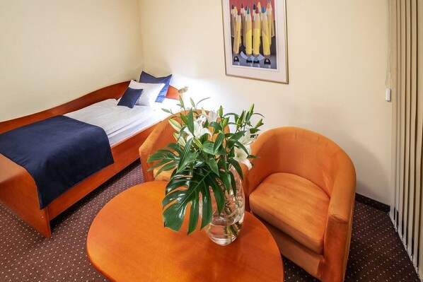 A hotel room with a bed, a chair, and a table with a plant. - Hotel Royal (Gliwice)