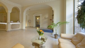 Eine geräumige Lobby mit einer Rezeption, gemütlichen Sitzgelegenheiten und einer Zimmerpflanze.