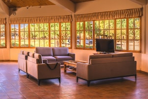 Una habitación amplia con ventanas grandes, un televisor de pantalla plana y un conjunto de sofás.