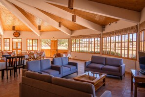 Un vaste espace intérieur doté de poutres en bois, de grandes fenêtres et de différents types de sièges.