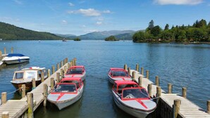 A calm lake with several boats docked at wooden piers.