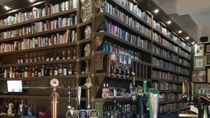A bar area with multiple taps, shelves of books, and a counter.
