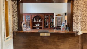 A reception desk with a "Reception" sign, wooden bookshelves, and a decorative arched window.