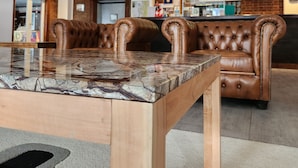 Un moderno vestíbulo con una mesa de mármol, sillones de cuero, una pared de ladrillo y un televisor.