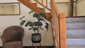 Una escalera con barandillas de madera, una silla de mimbre y una planta en maceta.