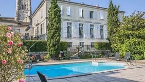 A swimming pool with lounge chairs and a building with a tower in the background.