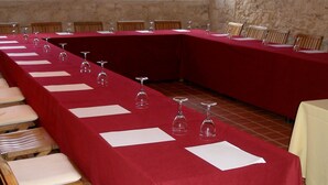 A long conference table with chairs, set up in a room with exposed brick walls and a window.