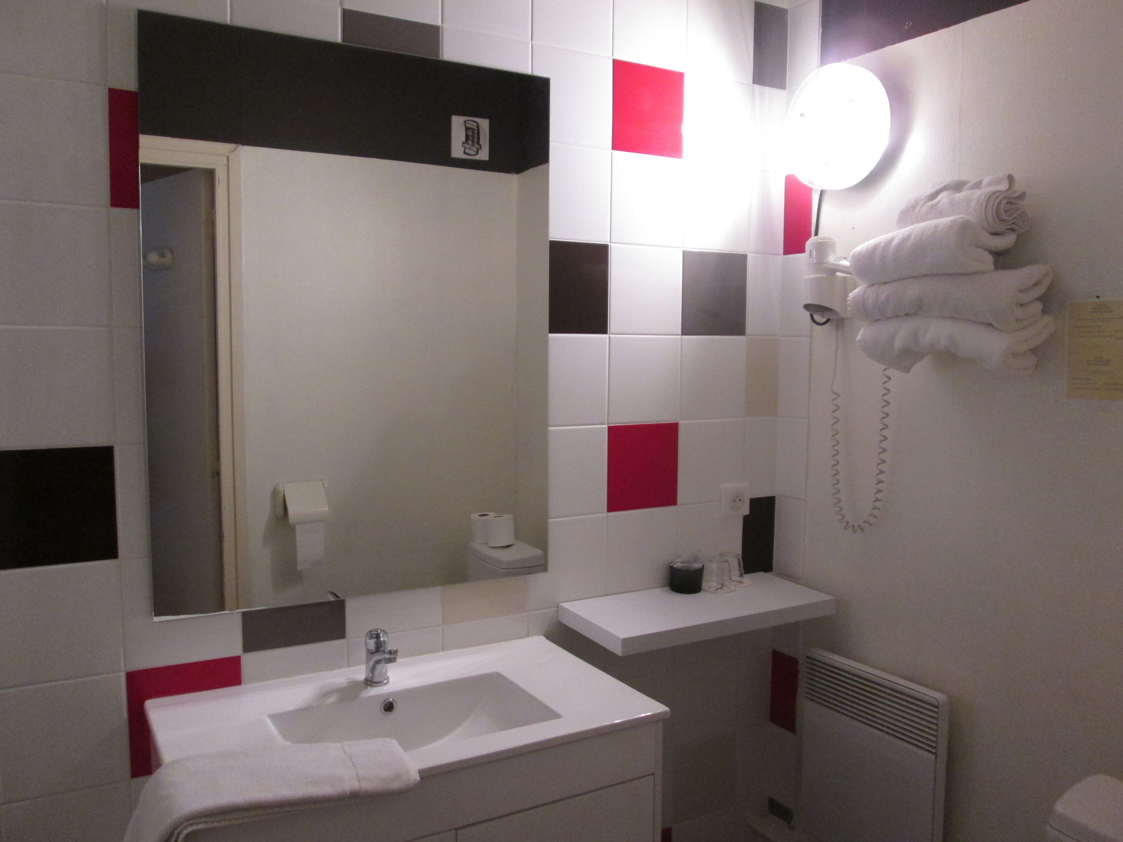 A bathroom with a sink, mirror, towel rack, and a wall-mounted light.