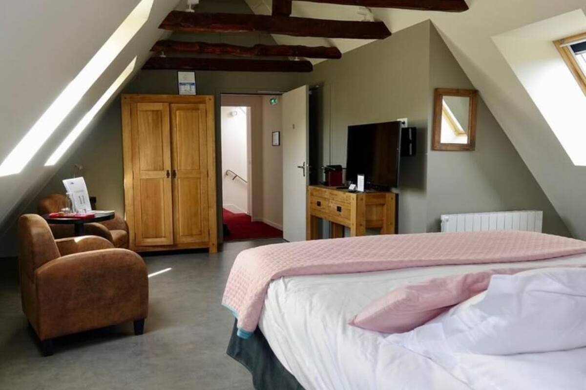 A bedroom with a bed, a desk, a chair, a wardrobe, and a television.