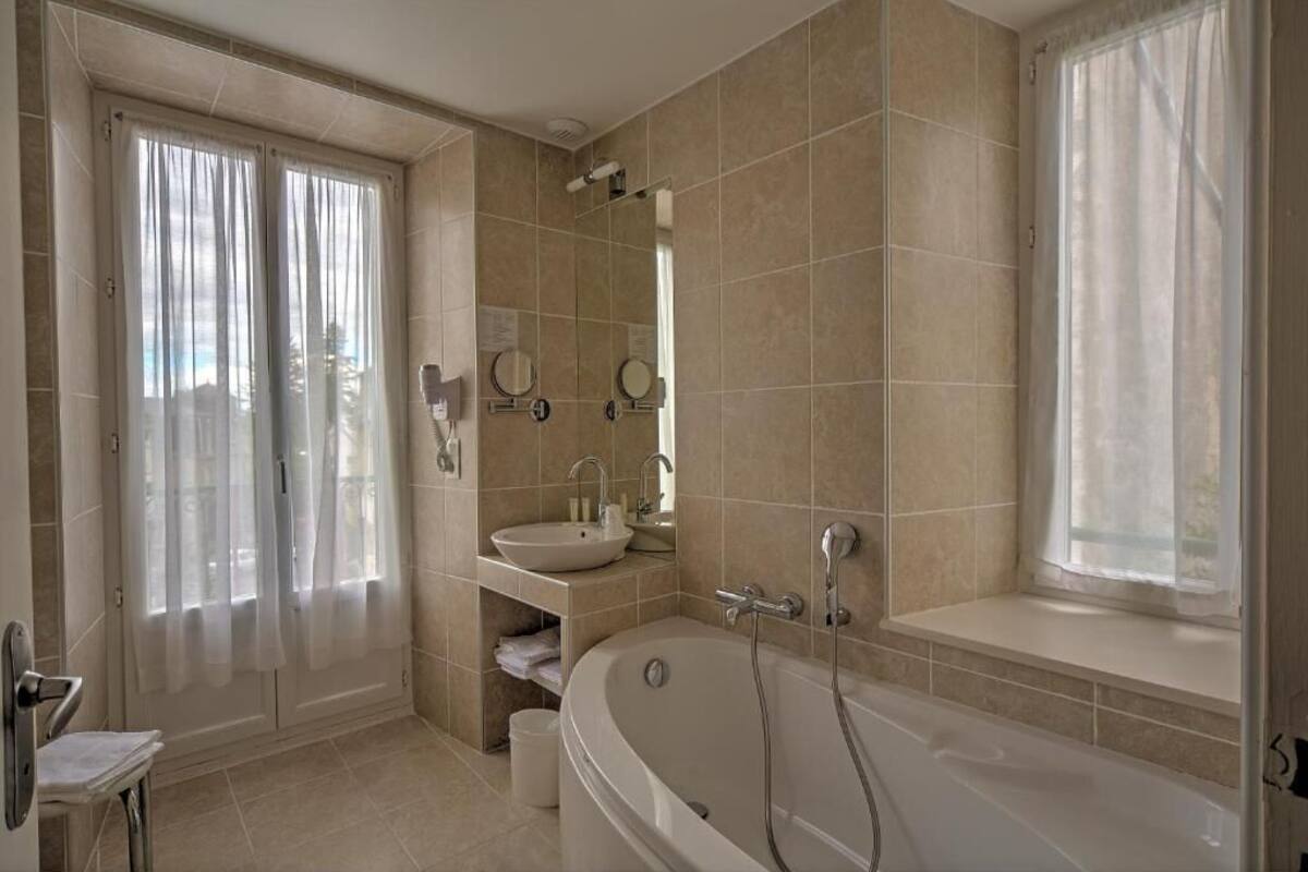 A bathroom with a bathtub, sink, and mirror.