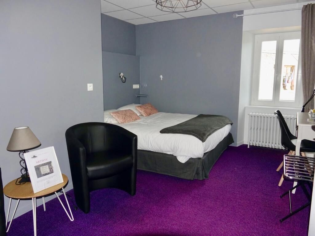 Een hotelkamer met een bed, een stoel, een bureau en een raam.