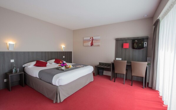 Habitación de hotel con cama, mesitas de noche, escritorio con silla, televisión y un cuadro en la pared.