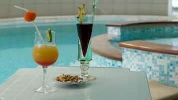 A poolside setting with two drinks, one in a glass and one in a tall glass with a straw.