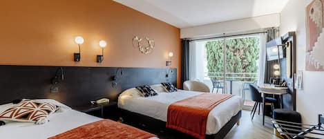 Habitación de hotel con dos camas, un escritorio, una silla, una mesita y un balcón con vistas a zonas verdes.