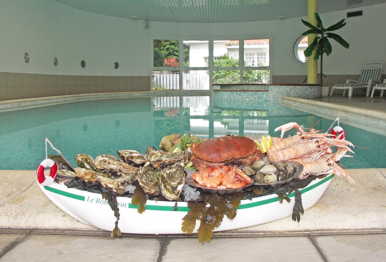 A seafood platter on a boat by a pool with a view of the pool and a plant in the background.