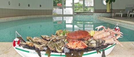 A seafood platter on a boat by a pool with a view of the pool and a plant in the background.