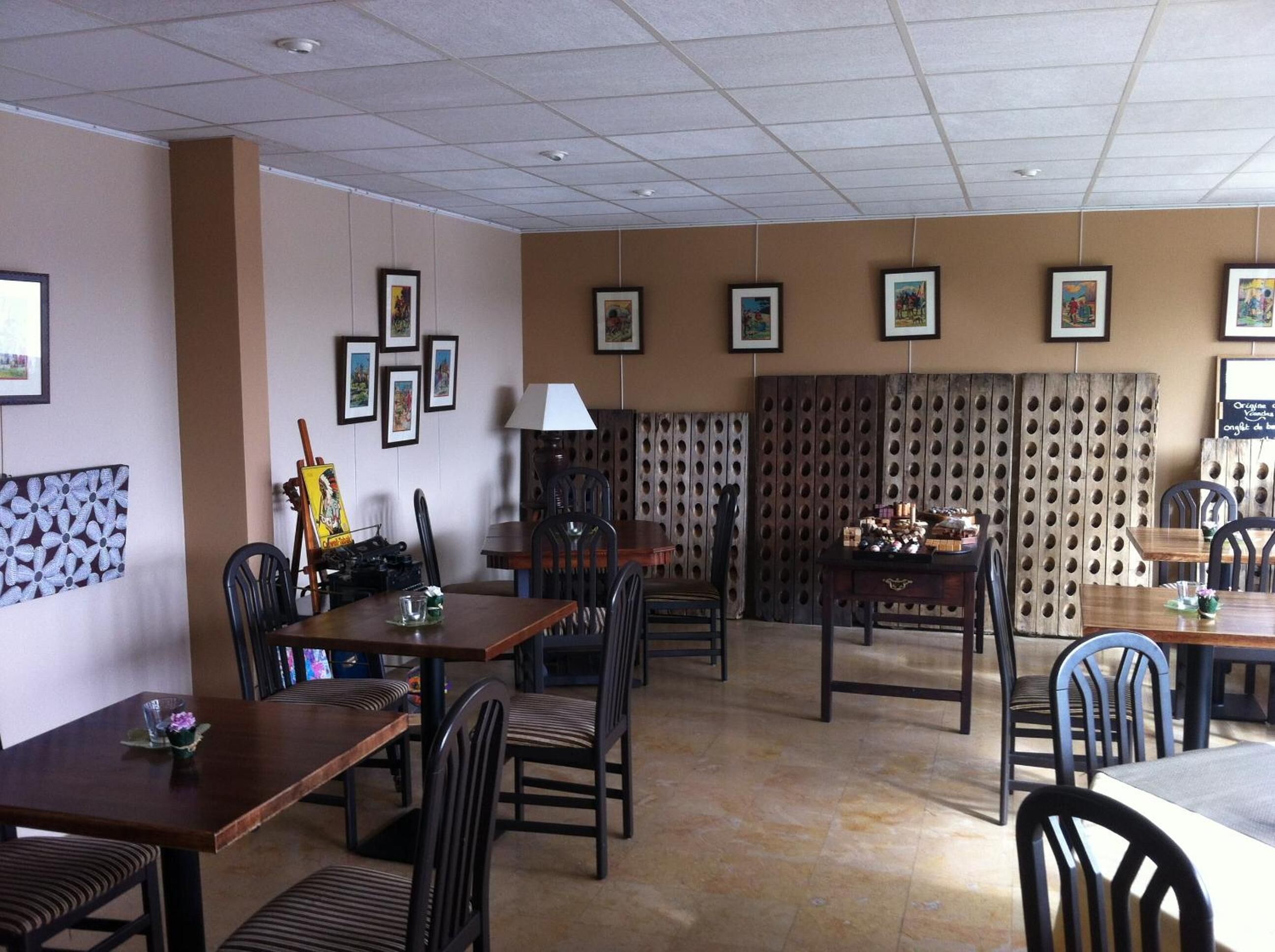 Un comedor con varias mesas y sillas, cuadros en las paredes y un panel decorativo con círculos.